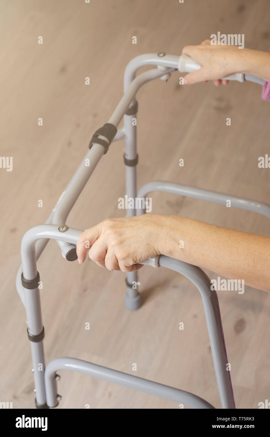 Le mani della donna anziana sulle maniglie di un deambulatore. Azioni di riabilitazione e di assistenza sanitaria concetto. Spazio di copia Foto Stock