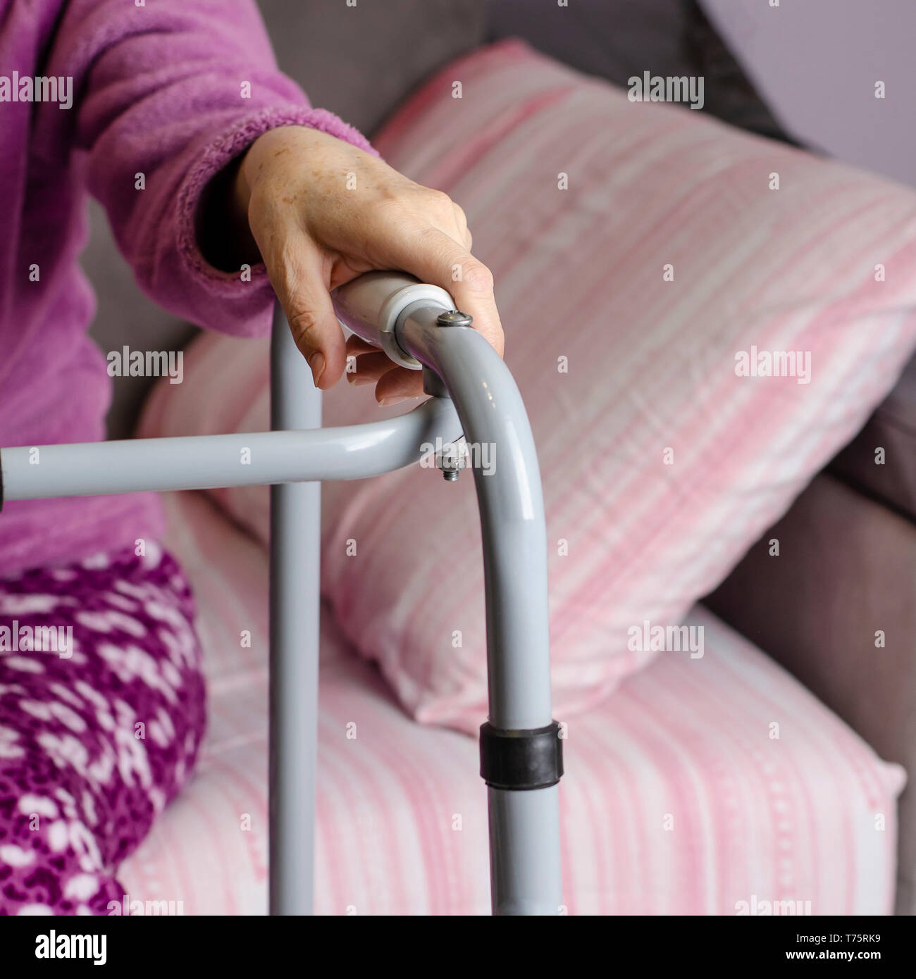 Le mani di una donna senior sulle maniglie di un deambulatore. Azioni di riabilitazione e di assistenza sanitaria concetto. Foto Stock