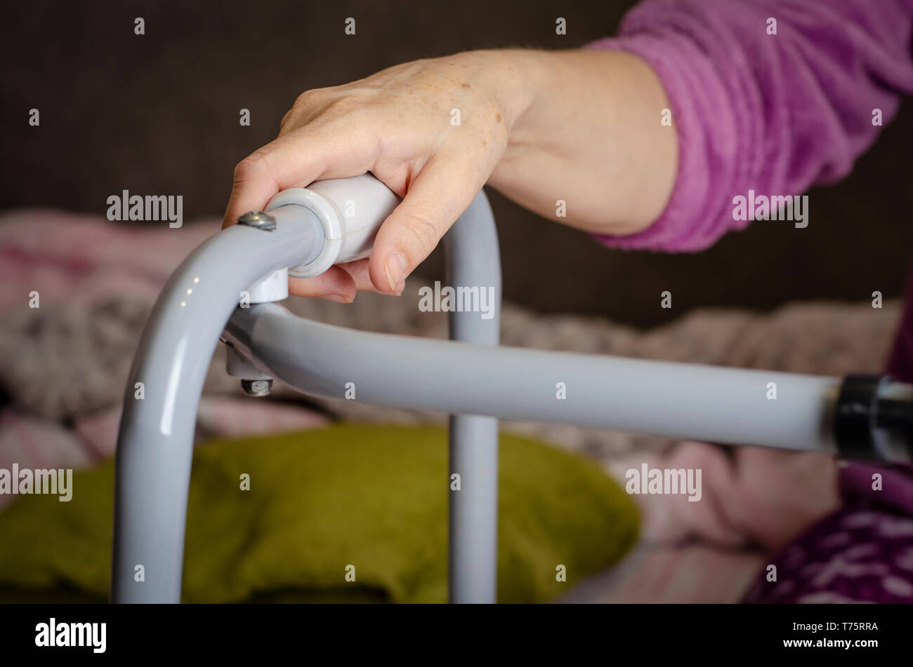 Le mani di una donna senior sulle maniglie di un deambulatore. Azioni di riabilitazione e di assistenza sanitaria concetto. Foto Stock
