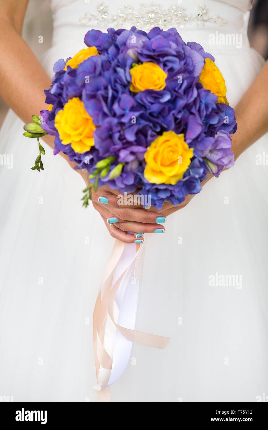 Irriconoscibile sposa tenendo un matrimonio bouquet di rose di colore giallo e viola ortensie Foto Stock