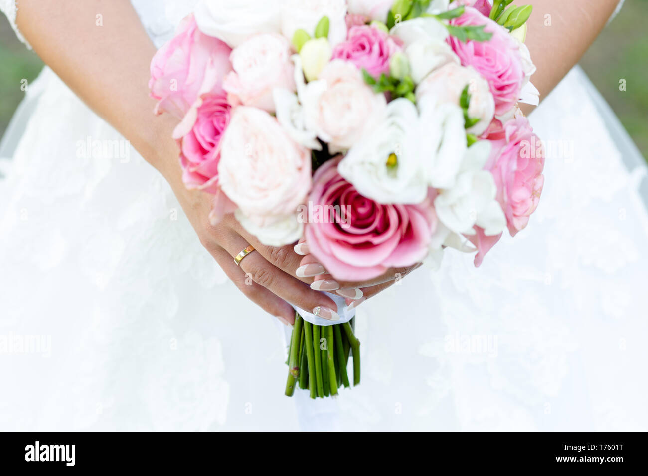 Wedding bouquet di rose e peonie bianco con freesias nelle mani di un irriconoscibile sposa Foto Stock