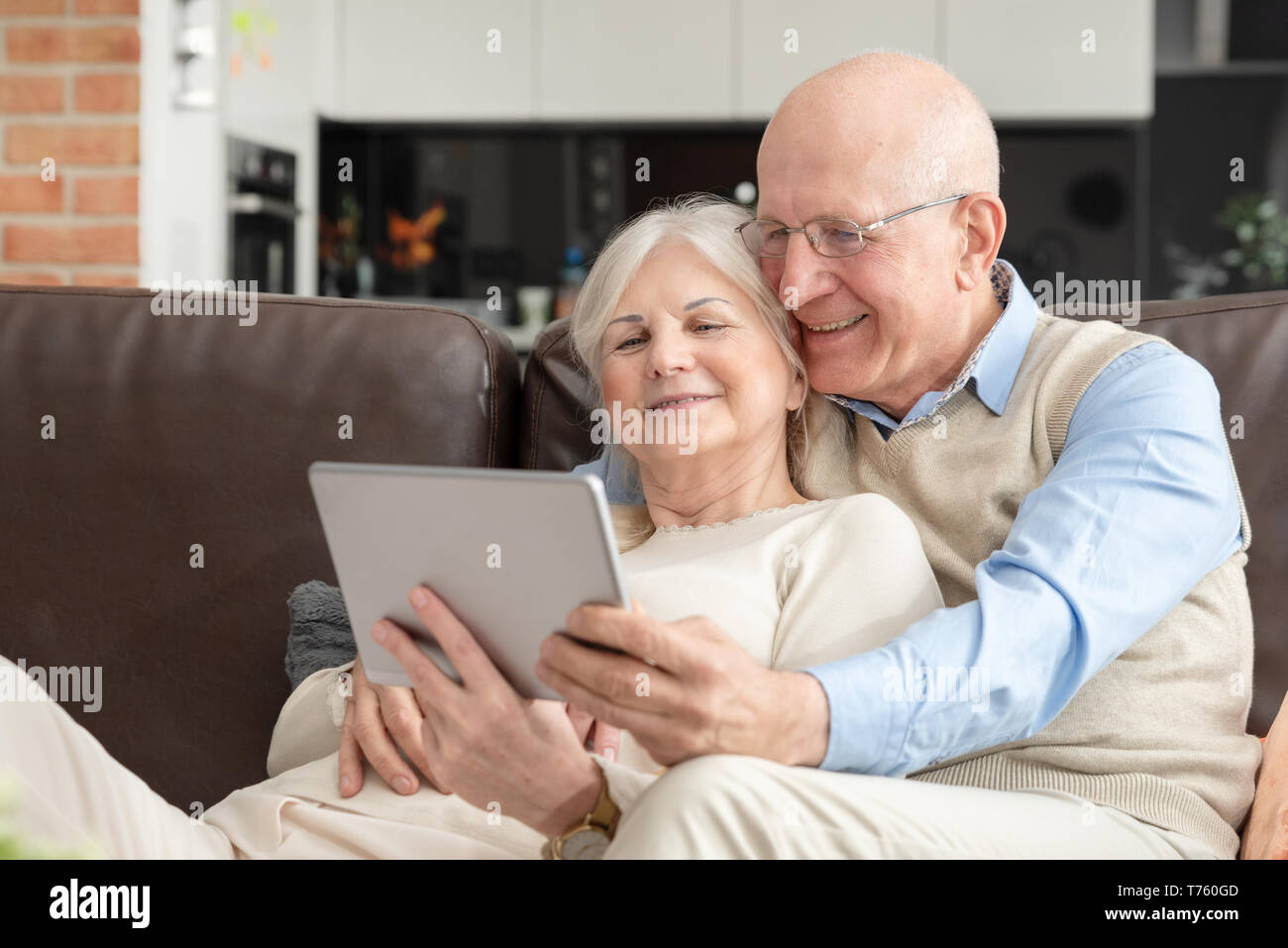 Coppia senior con tavoletta digitale a casa. Nonni con i social media. Foto Stock