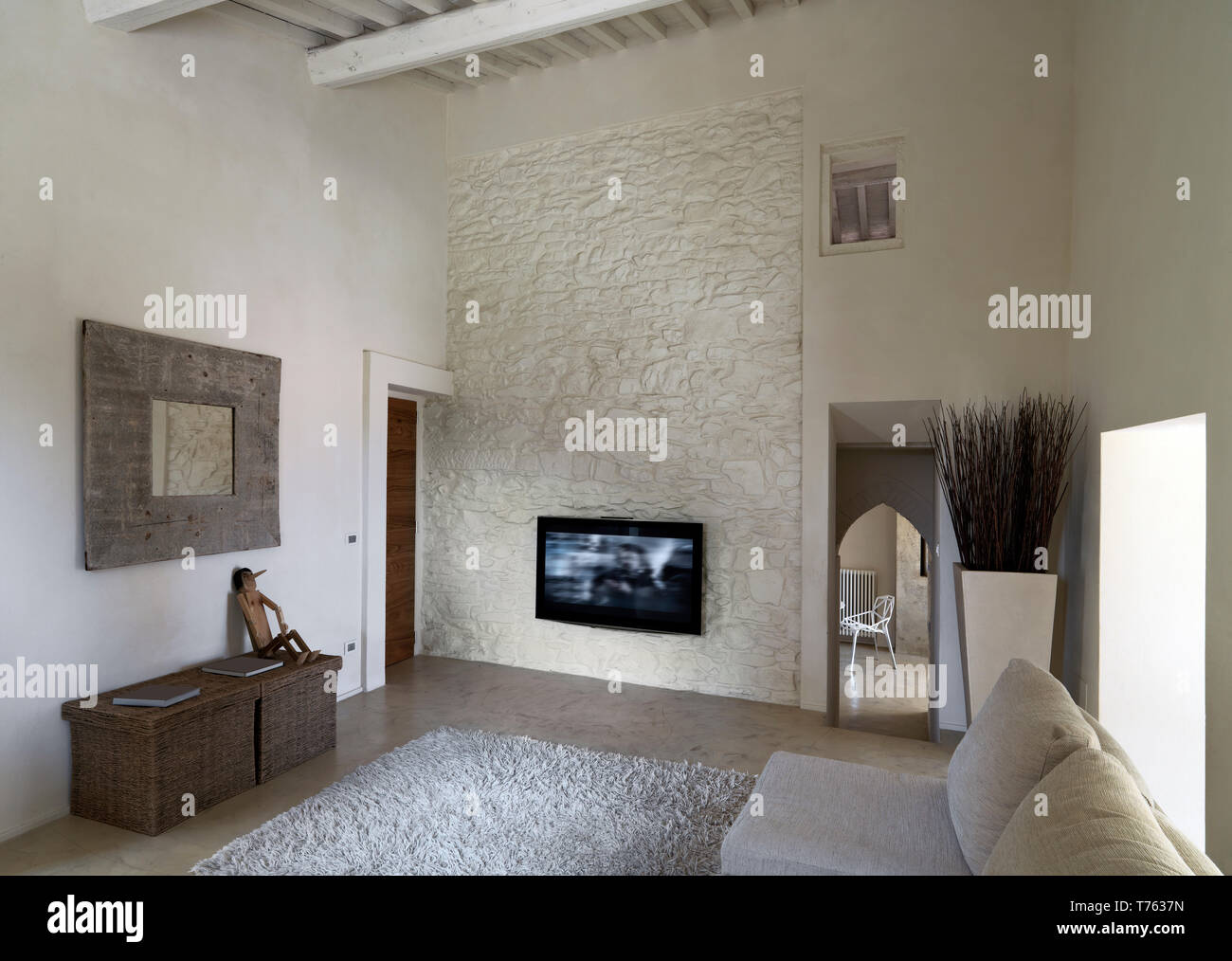Scatti di interni di un soggiorno con pavimento in calcestruzzo e muratura in pietra il soffitto è realizzato in legno Foto Stock