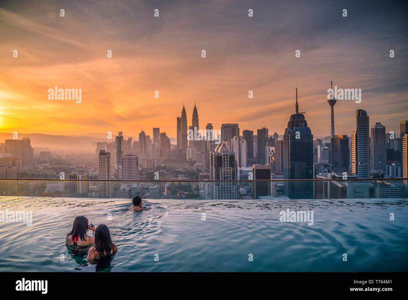 Traveler cercando vista sullo skyline di Kuala Lumpur City in piscina sul tetto dell'hotel a sunrise di Kuala Lumpur in Malesia. Foto Stock