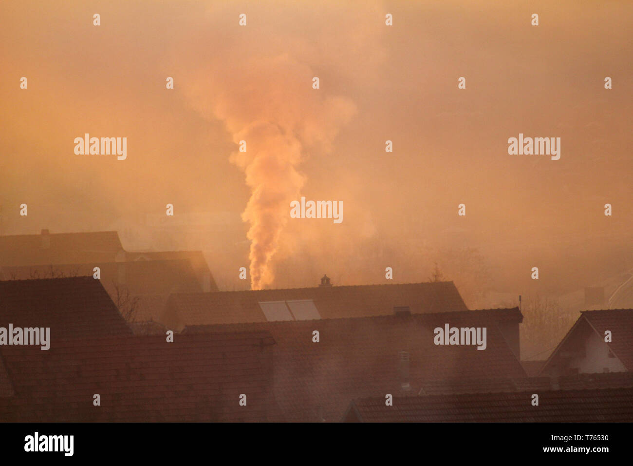 Comignoli fumanti in corrispondenza di tetti di case emette fumo, smog all'alba, inquinanti entrano nell'atmosfera. Catastrofe ambientale. Le emissioni nocive e di scarico. Foto Stock