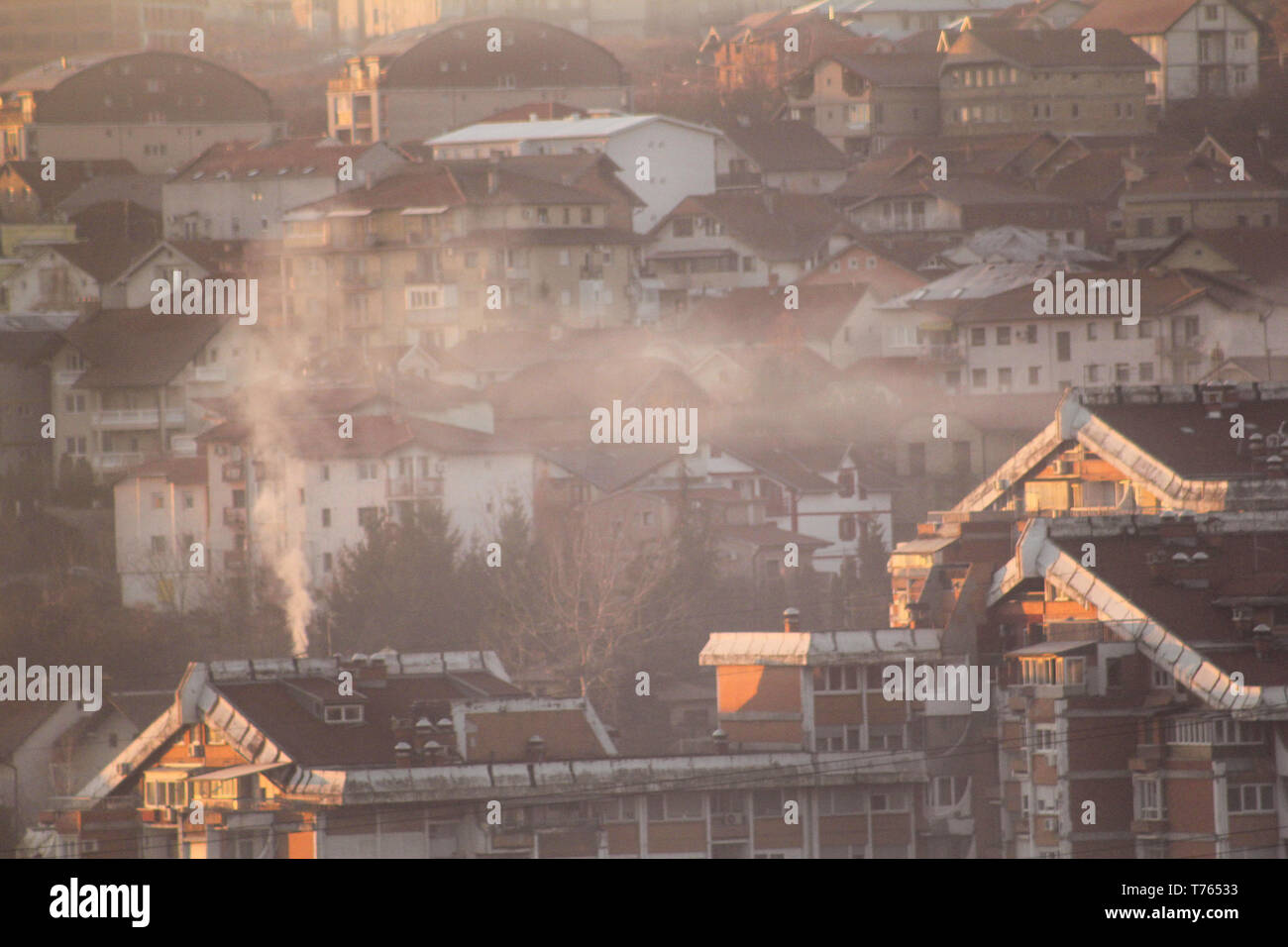 Comignoli fumanti in corrispondenza di tetti di case emette fumo, smog all'alba, inquinanti entrano nell'atmosfera. Catastrofe ambientale. Le emissioni nocive e di scarico. Foto Stock