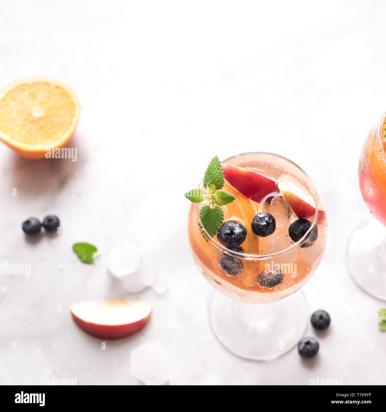 Vino bianco Sangria bevanda con frutta e mirtilli su marmo bianco, copia dello spazio. Vetro a freddo estate bianco ghiacciato sangria cocktail. Foto Stock