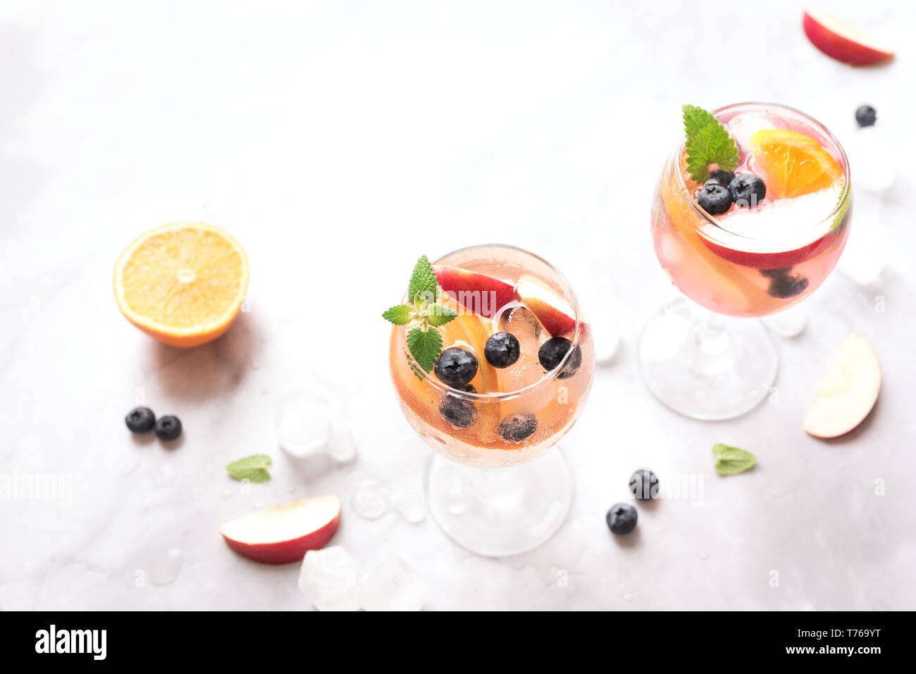 Vino bianco Sangria bevanda con frutta e mirtilli su marmo bianco, copia dello spazio. Vetro a freddo estate bianco ghiacciato sangria cocktail. Foto Stock