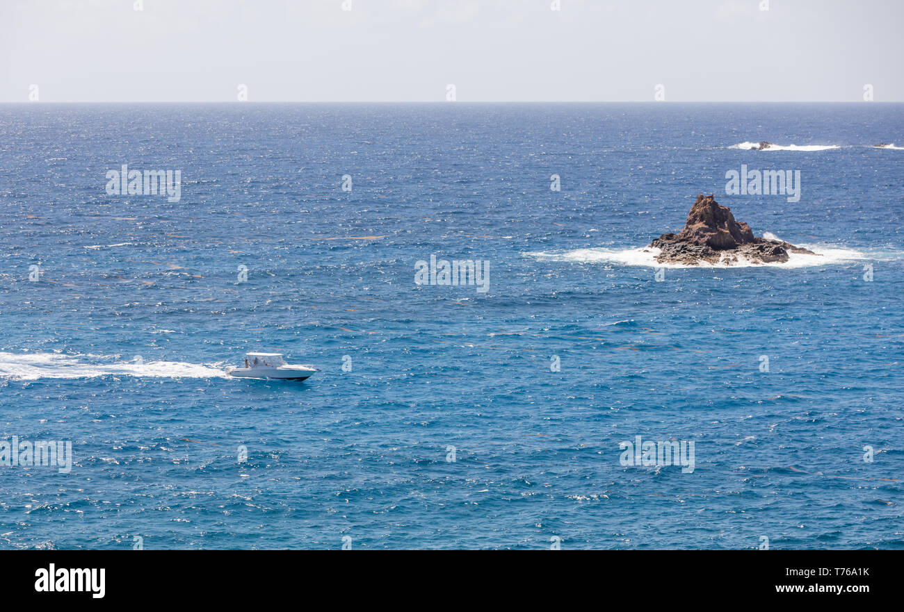 Power Boat off Grand Fond con una piccola isola di roccia, St Barts Foto Stock