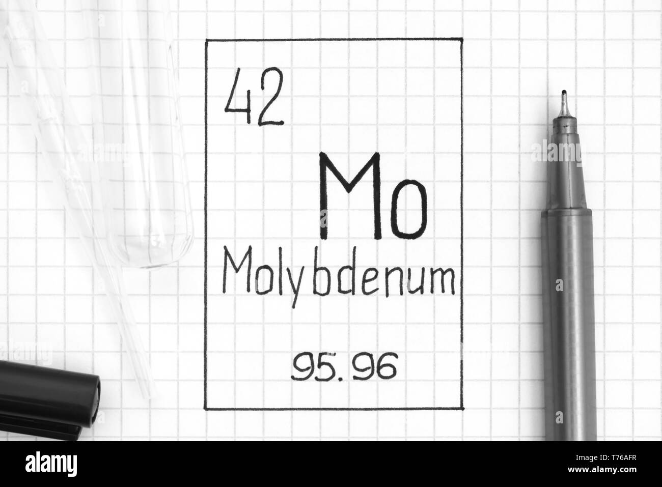 Tavola periodica degli elementi. La grafia elemento chimico molibdeno Mo con la penna nera, tubo di prova e la pipetta. Close-up. Foto Stock