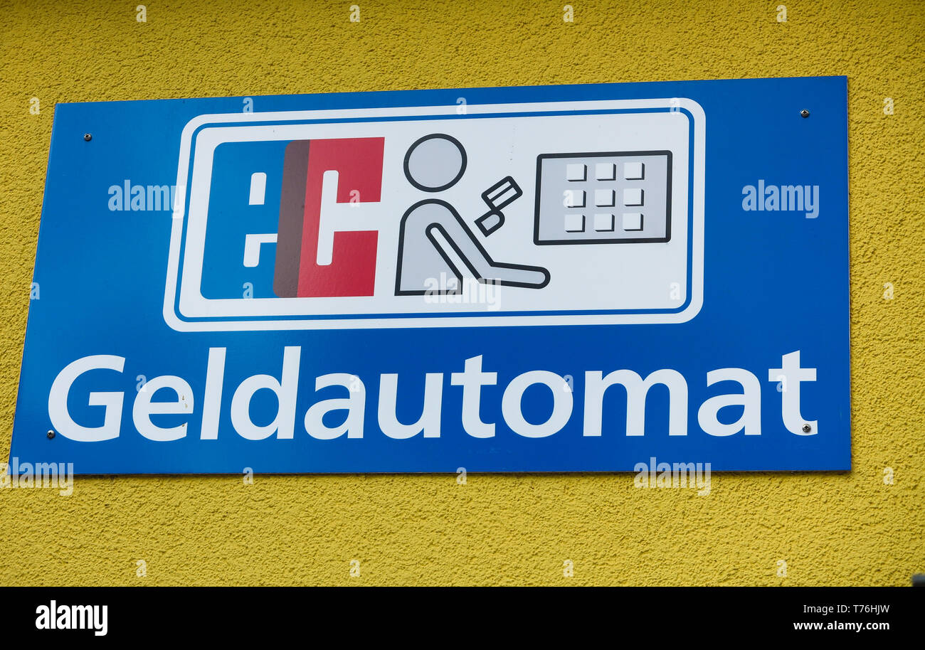 Vista su isolati segno blu sulla parete gialla che indica l'ATM (tedesco lettere "Geldautomat' significa automatic teller machine) Foto Stock