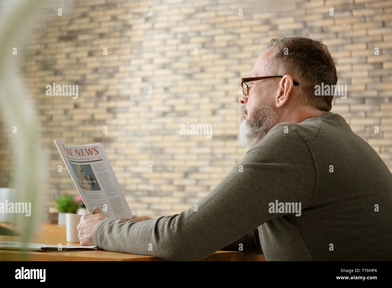 Senior uomo che legge il giornale in cafe Foto Stock