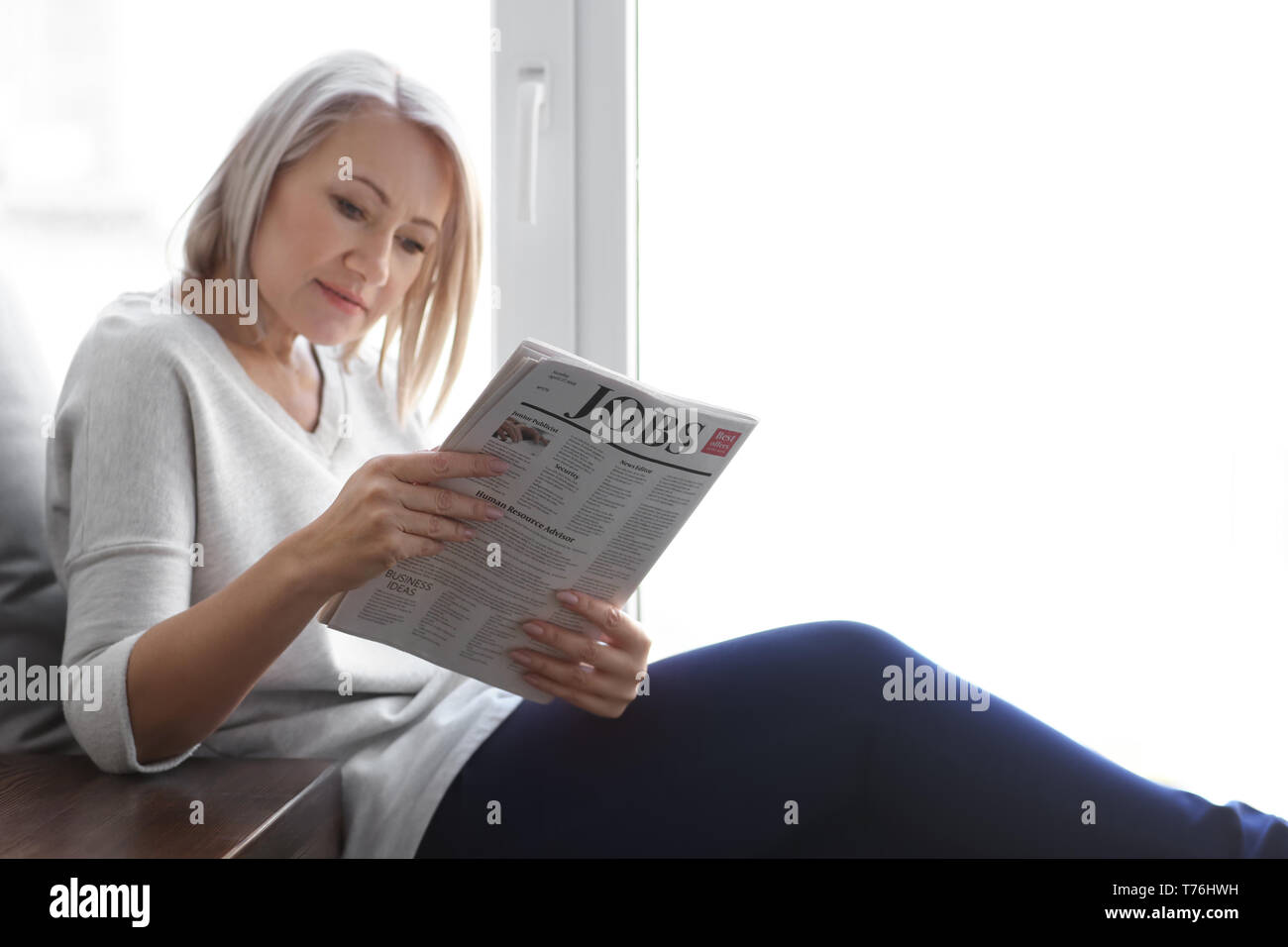 Donna matura la lettura quotidiano a casa Foto Stock