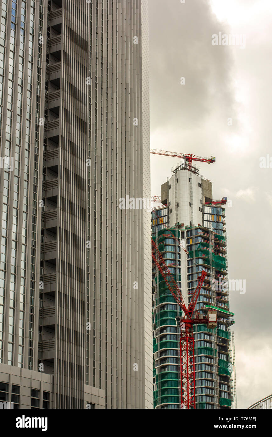 Il grattacielo e la costruzione di un grattacielo. Il centro della città è costruito su edifici alti. Urbanizzazione e industria edilizia. La torre della gru. Foto Stock
