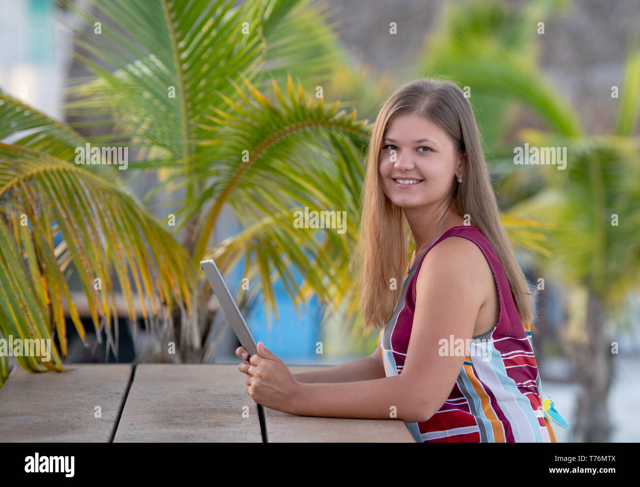 Giovane donna che indossa abiti utilizzando tablet sulla spiaggia al mattino sullo sfondo di palme in Florida Foto Stock Giovane donna che indossa abiti utilizzando tablet sulla spiaggia al mattino sullo sfondo di palme in Florida Foto Stock