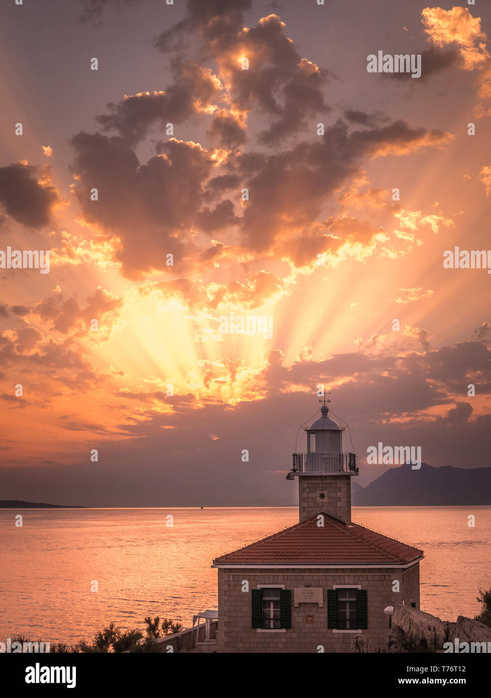 Bellissimo tramonto sul mare Mediterraneo con il faro in primo piano a Makarska, Croazia Foto Stock