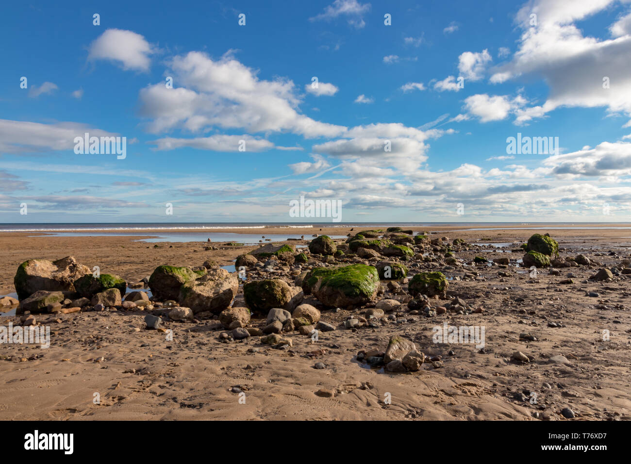 Le rocce in primo piano su un Fraisthorpe deserta spiaggia nei pressi di Bridlington in North Yorkshire in una giornata di sole Foto Stock