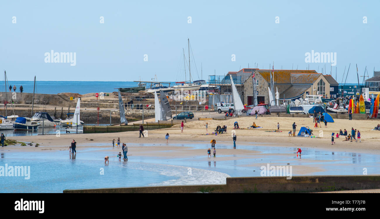 Lyme Regis, Dorset, Regno Unito. Il 5 maggio 2019. Regno Unito: Meteo visitatori godere di caldo e soleggiato incantesimi con una leggera brezza sulla spiaggia a Lyme Regis. Le condizioni dello scambiatore di calore sono previsti per il week-end festivo di maggio. Credito: Celia McMahon/Alamy Live News. Foto Stock