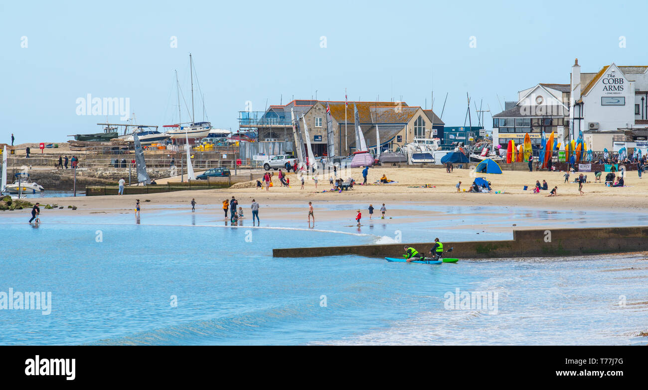 Lyme Regis, Dorset, Regno Unito. Il 5 maggio 2019. Regno Unito: Meteo visitatori godere di caldo e soleggiato incantesimi con una leggera brezza sulla spiaggia a Lyme Regis. Le condizioni dello scambiatore di calore sono previsti per il week-end festivo di maggio. Credito: Celia McMahon/Alamy Live News. Foto Stock