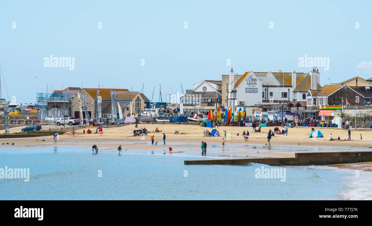 Lyme Regis, Dorset, Regno Unito. Il 5 maggio 2019. Regno Unito: Meteo visitatori godere di caldo e soleggiato incantesimi con una leggera brezza sulla spiaggia a Lyme Regis. Le condizioni dello scambiatore di calore sono previsti per il week-end festivo di maggio. Credito: Celia McMahon/Alamy Live News. Foto Stock