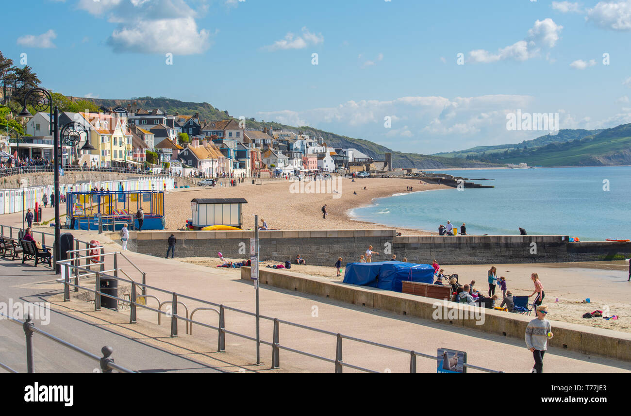 Lyme Regis, Dorset, Regno Unito. Il 5 maggio 2019. Regno Unito: Meteo visitatori godere di caldo e soleggiato incantesimi con una leggera brezza sulla spiaggia a Lyme Regis. Le condizioni dello scambiatore di calore sono previsti per il week-end festivo di maggio. Credito: Celia McMahon/Alamy Live News. Foto Stock