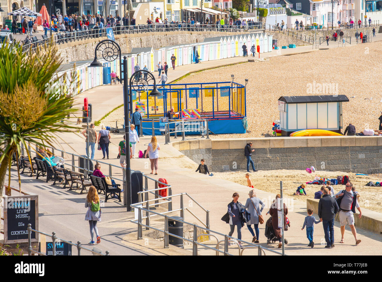 Lyme Regis, Dorset, Regno Unito. Il 5 maggio 2019. Regno Unito: Meteo visitatori godere di caldo e soleggiato incantesimi con una leggera brezza sulla spiaggia a Lyme Regis. Le condizioni dello scambiatore di calore sono previsti per il week-end festivo di maggio. Credito: Celia McMahon/Alamy Live News. Foto Stock