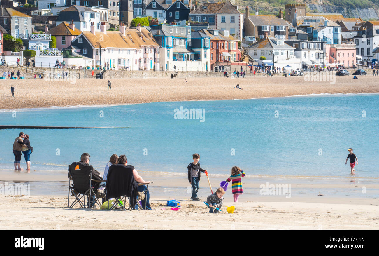 Lyme Regis, Dorset, Regno Unito. Il 5 maggio 2019. Regno Unito: Meteo visitatori godere di caldo e soleggiato incantesimi con una leggera brezza sulla spiaggia a Lyme Regis. Le condizioni dello scambiatore di calore sono previsti per il week-end festivo di maggio. Credito: Celia McMahon/Alamy Live News. Foto Stock