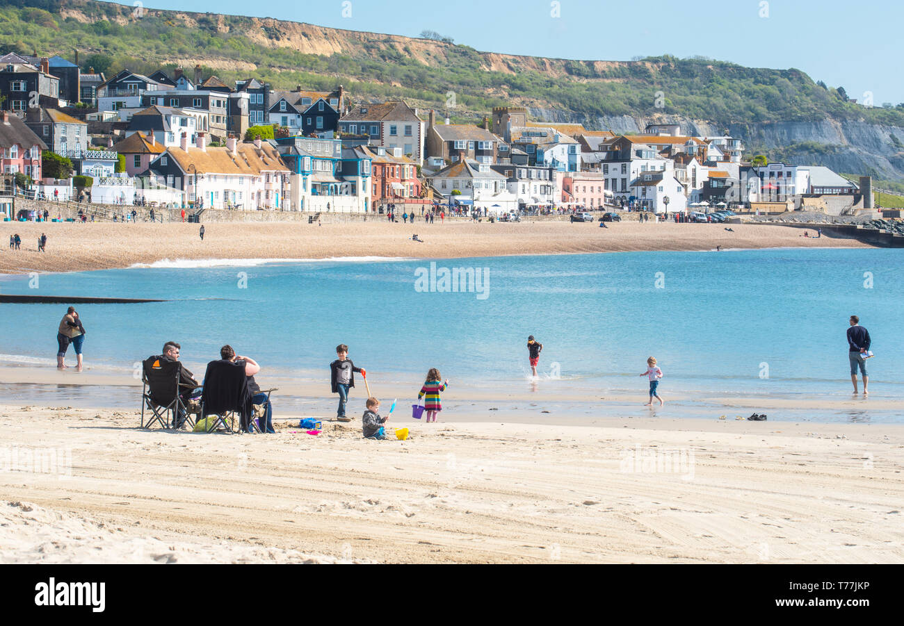 Lyme Regis, Dorset, Regno Unito. Il 5 maggio 2019. Regno Unito: Meteo visitatori godere di caldo e soleggiato incantesimi con una leggera brezza sulla spiaggia a Lyme Regis. Le condizioni dello scambiatore di calore sono previsti per il week-end festivo di maggio. Credito: Celia McMahon/Alamy Live News. Foto Stock