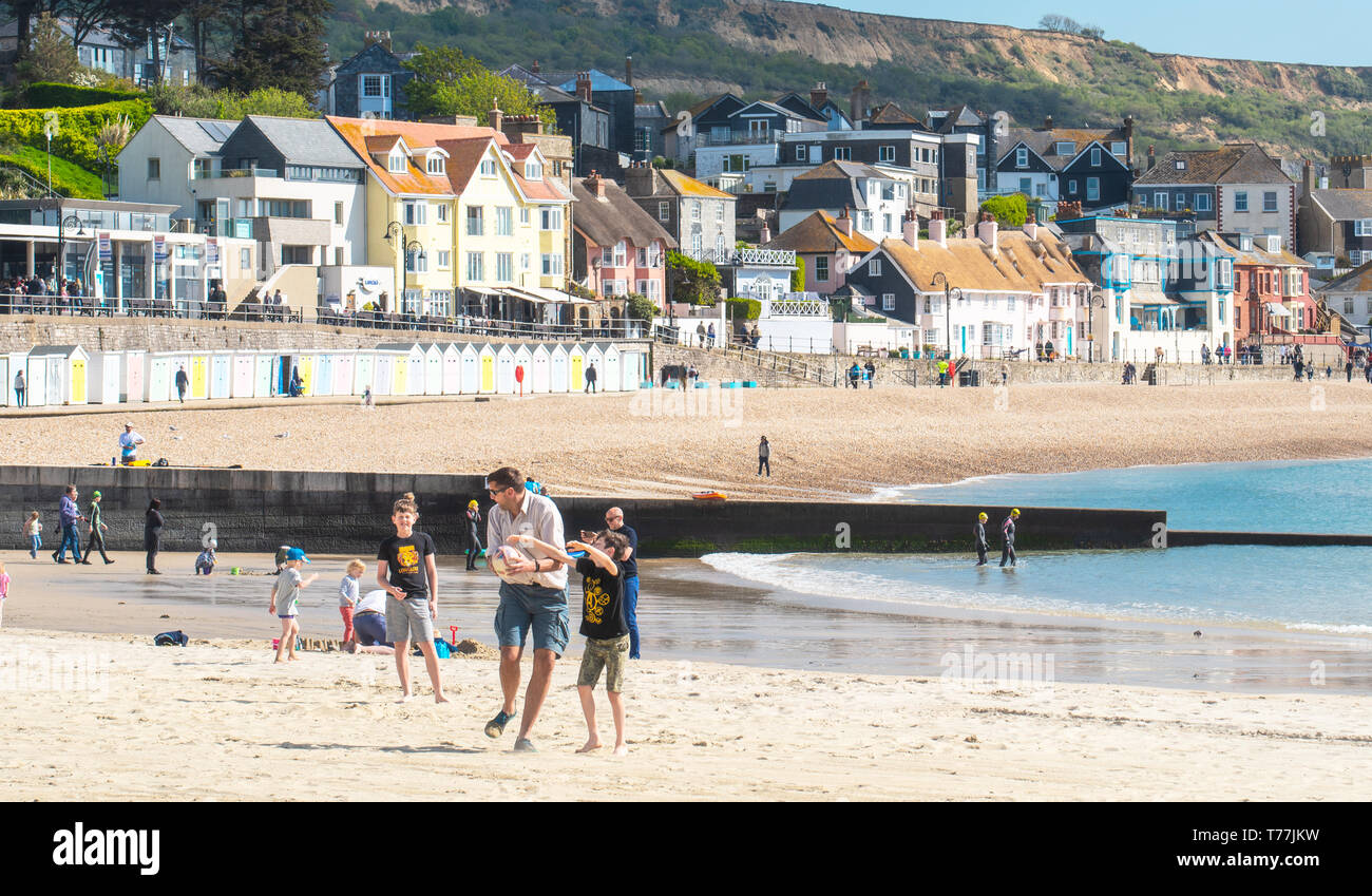 Lyme Regis, Dorset, Regno Unito. Il 5 maggio 2019. Regno Unito: Meteo visitatori godere di caldo e soleggiato incantesimi con una leggera brezza sulla spiaggia a Lyme Regis. Le condizioni dello scambiatore di calore sono previsti per il week-end festivo di maggio. Credito: Celia McMahon/Alamy Live News. Foto Stock