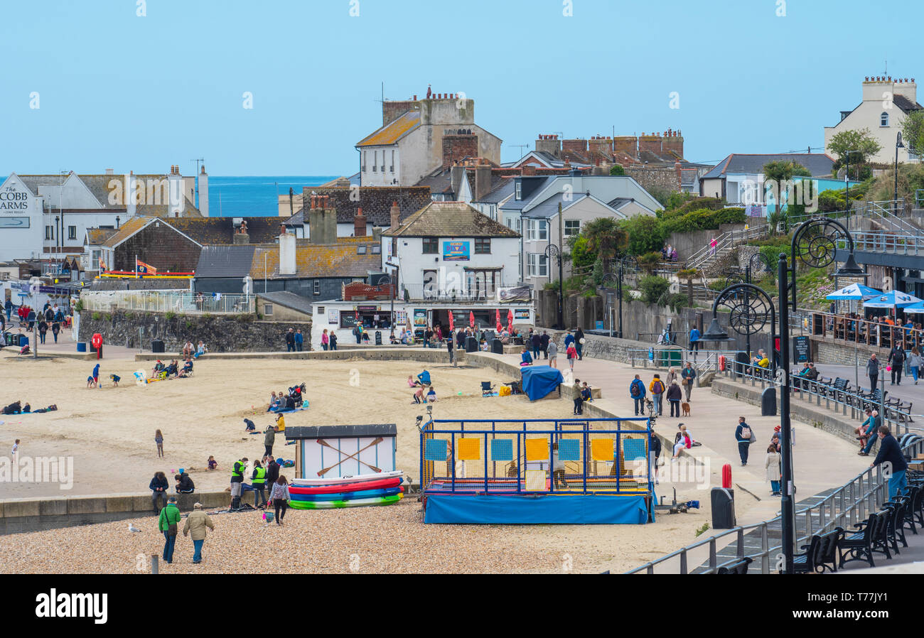 Lyme Regis, Dorset, Regno Unito. Il 5 maggio 2019. Regno Unito: Meteo visitatori godere di caldo e soleggiato incantesimi con una leggera brezza sulla spiaggia a Lyme Regis. Le condizioni dello scambiatore di calore sono previsti per il week-end festivo di maggio. Credito: Celia McMahon/Alamy Live News. Foto Stock