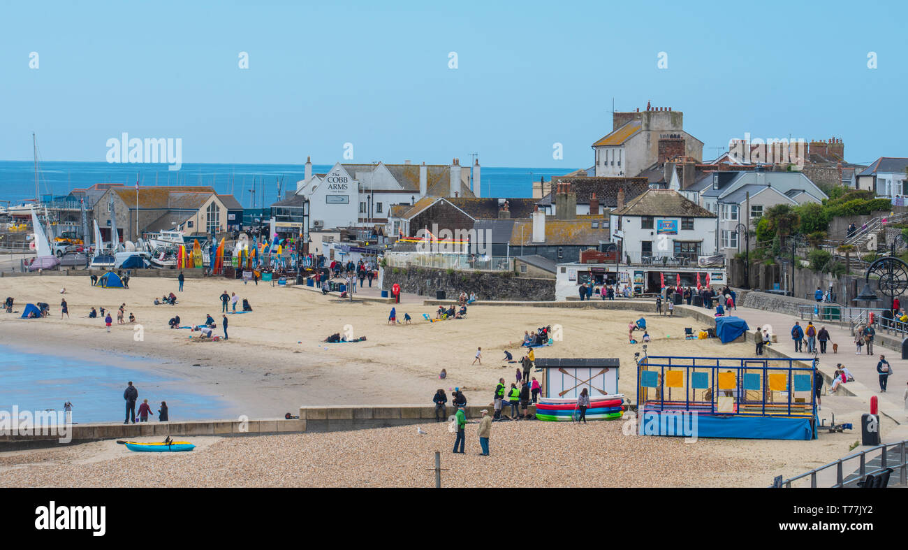 Lyme Regis, Dorset, Regno Unito. Il 5 maggio 2019. Regno Unito: Meteo visitatori godere di caldo e soleggiato incantesimi con una leggera brezza sulla spiaggia a Lyme Regis. Le condizioni dello scambiatore di calore sono previsti per il week-end festivo di maggio. Credito: Celia McMahon/Alamy Live News. Foto Stock