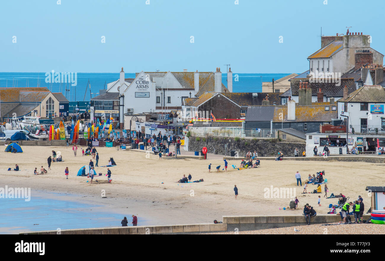 Lyme Regis, Dorset, Regno Unito. Il 5 maggio 2019. Regno Unito: Meteo visitatori godere di caldo e soleggiato incantesimi con una leggera brezza sulla spiaggia a Lyme Regis. Le condizioni dello scambiatore di calore sono previsti per il week-end festivo di maggio. Credito: Celia McMahon/Alamy Live News. Foto Stock