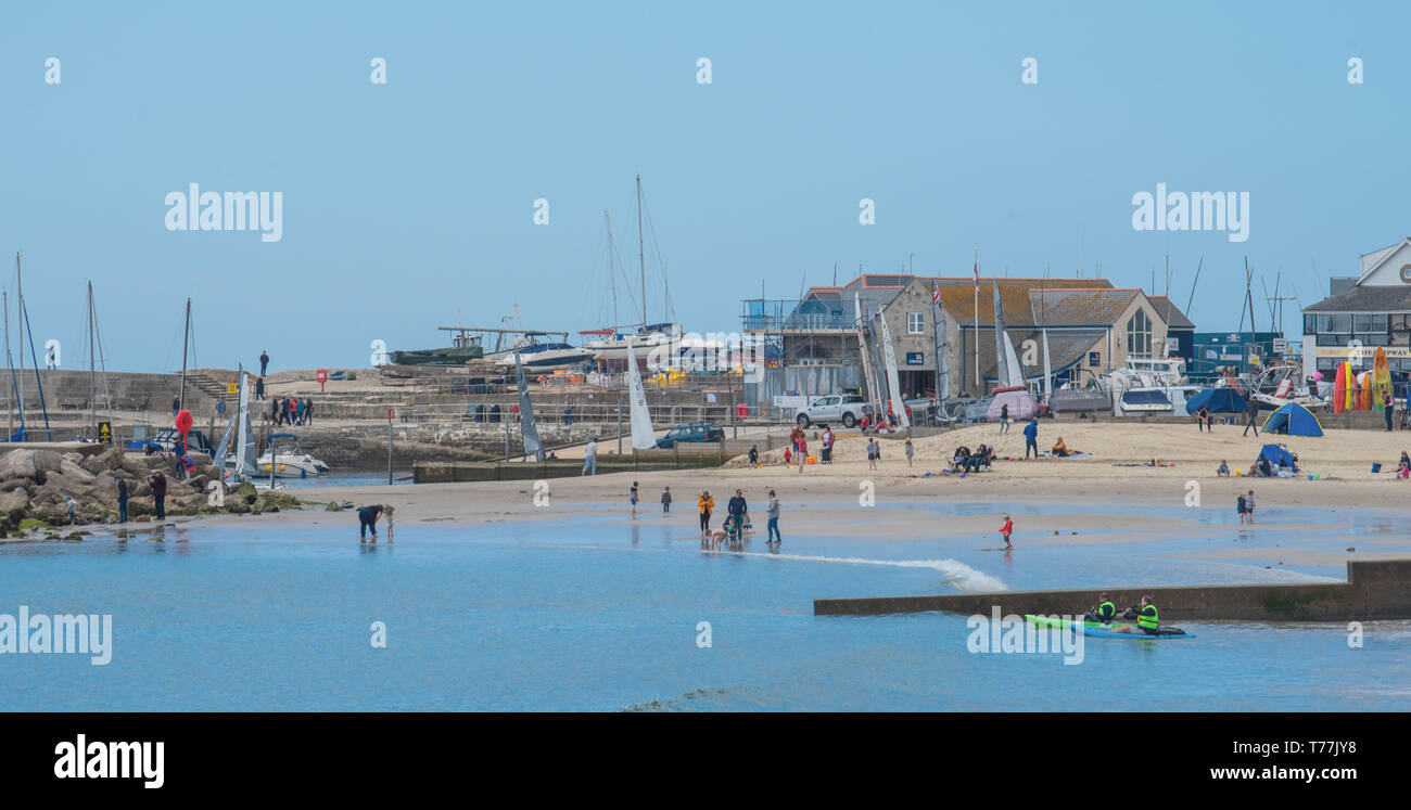 Lyme Regis, Dorset, Regno Unito. Il 5 maggio 2019. Regno Unito: Meteo visitatori godere di caldo e soleggiato incantesimi con una leggera brezza sulla spiaggia a Lyme Regis. Le condizioni dello scambiatore di calore sono previsti per il week-end festivo di maggio. Credito: Celia McMahon/Alamy Live News. Foto Stock