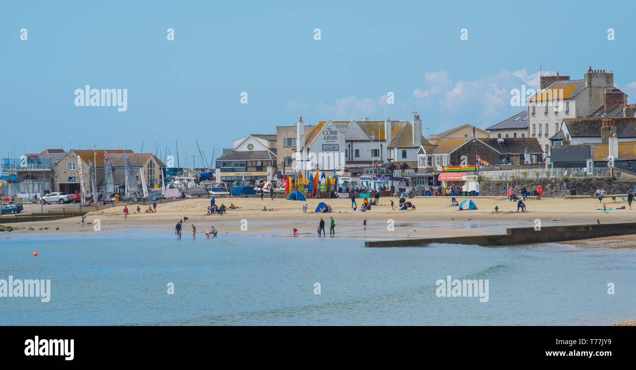 Lyme Regis, Dorset, Regno Unito. Il 5 maggio 2019. Regno Unito: Meteo visitatori godere di caldo e soleggiato incantesimi con una leggera brezza sulla spiaggia a Lyme Regis. Le condizioni dello scambiatore di calore sono previsti per il week-end festivo di maggio. Credito: Celia McMahon/Alamy Live News. Foto Stock