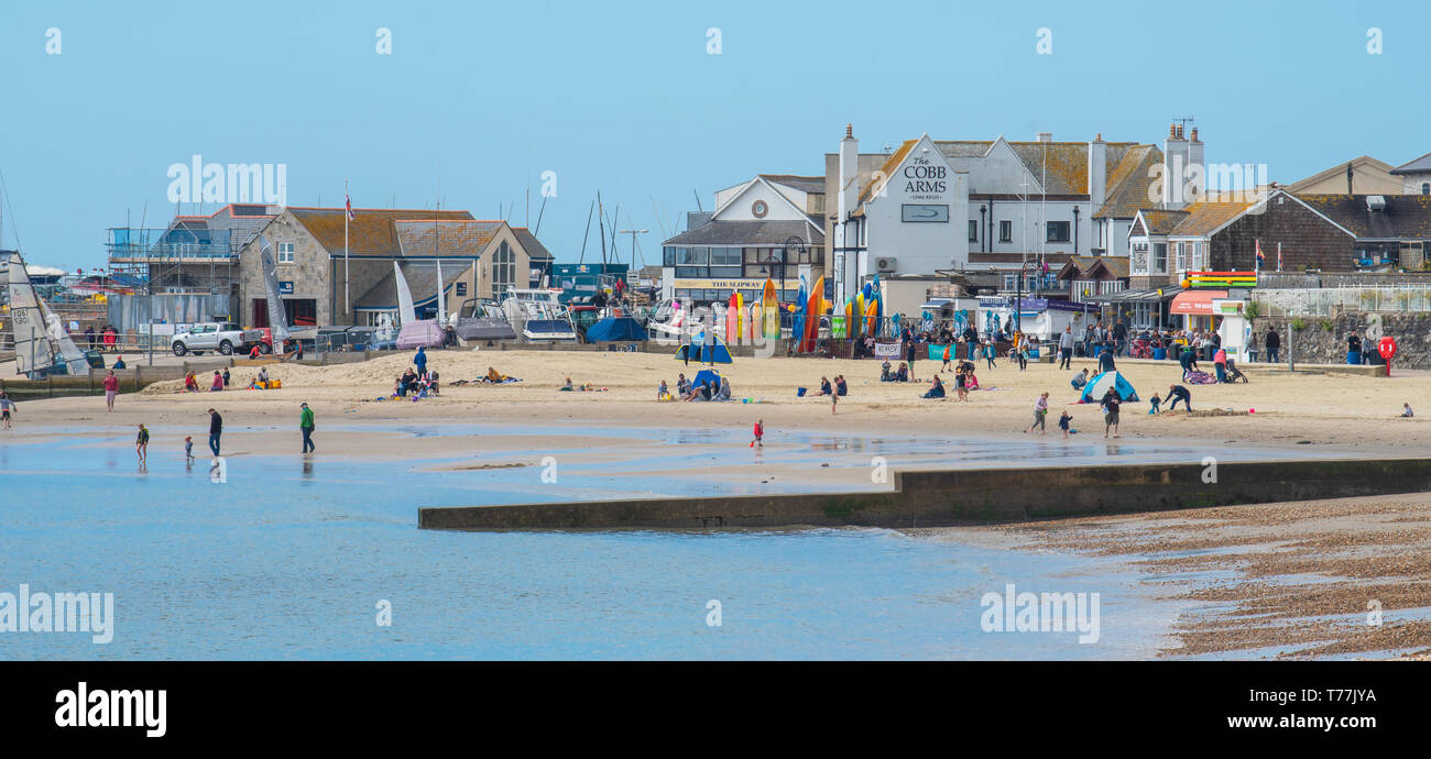 Lyme Regis, Dorset, Regno Unito. Il 5 maggio 2019. Regno Unito: Meteo visitatori godere di caldo e soleggiato incantesimi con una leggera brezza sulla spiaggia a Lyme Regis. Le condizioni dello scambiatore di calore sono previsti per il week-end festivo di maggio. Credito: Celia McMahon/Alamy Live News. Foto Stock