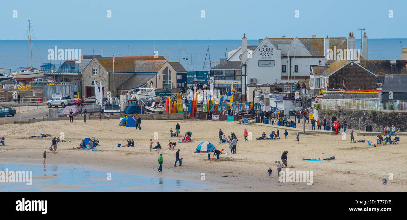 Lyme Regis, Dorset, Regno Unito. Il 5 maggio 2019. Regno Unito: Meteo visitatori godere di caldo e soleggiato incantesimi con una leggera brezza sulla spiaggia a Lyme Regis. Le condizioni dello scambiatore di calore sono previsti per il week-end festivo di maggio. Credito: Celia McMahon/Alamy Live News. Foto Stock