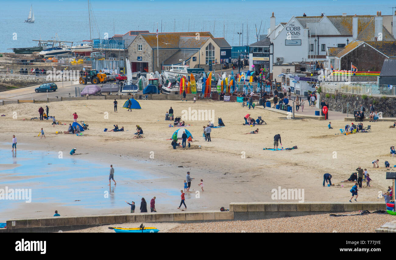Lyme Regis, Dorset, Regno Unito. Il 5 maggio 2019. Regno Unito: Meteo visitatori godere di caldo e soleggiato incantesimi con una leggera brezza sulla spiaggia a Lyme Regis. Le condizioni dello scambiatore di calore sono previsti per il week-end festivo di maggio. Credito: Celia McMahon/Alamy Live News. Foto Stock