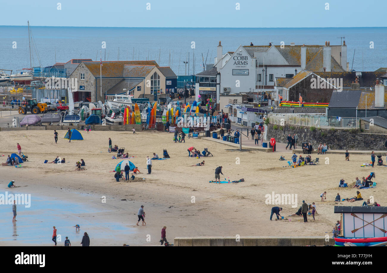 Lyme Regis, Dorset, Regno Unito. Il 5 maggio 2019. Regno Unito: Meteo visitatori godere di caldo e soleggiato incantesimi con una leggera brezza sulla spiaggia a Lyme Regis. Le condizioni dello scambiatore di calore sono previsti per il week-end festivo di maggio. Credito: Celia McMahon/Alamy Live News. Foto Stock
