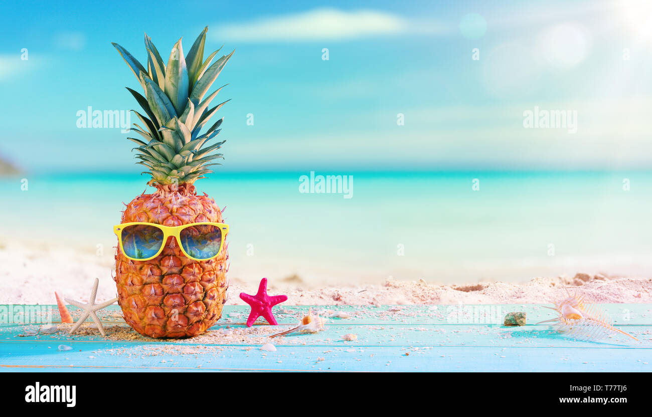 Ananas con occhiali da sole in spiaggia Foto Stock