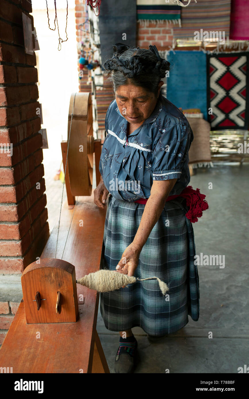 La donna è la filatura della fibra di lana sul mulo di filatura per formare un trefolo di filo. Teotitlan del Valle, Oaxaca, Messico. Apr 2019 Foto Stock