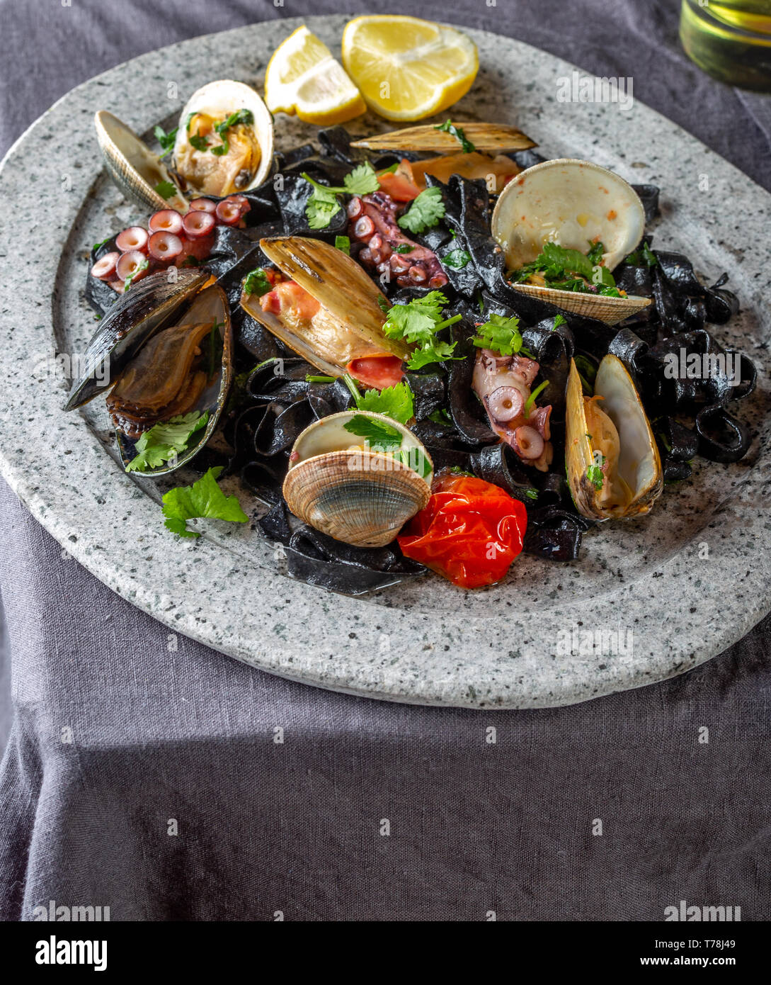 Frutti di mare fettuccine nero fehttuchini. Pasta di colore nero con calamari, polpi vongole, cozze sulla lastra di pietra. Piatto Gourmet. Foto Stock