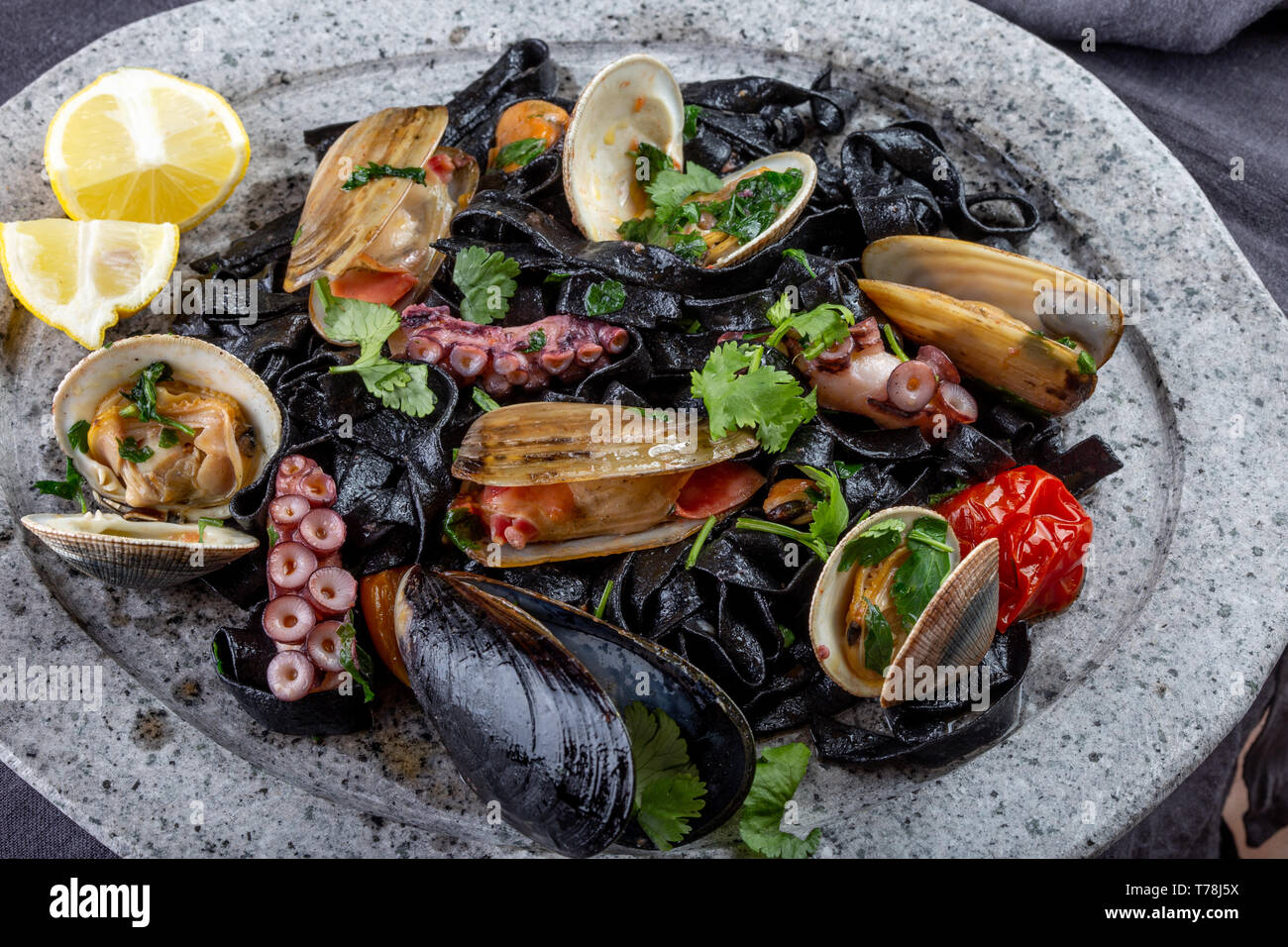 Frutti di mare fettuccine nero fehttuchini. Pasta di colore nero con calamari, polpi vongole, cozze sulla lastra di pietra. Piatto Gourmet. Foto Stock