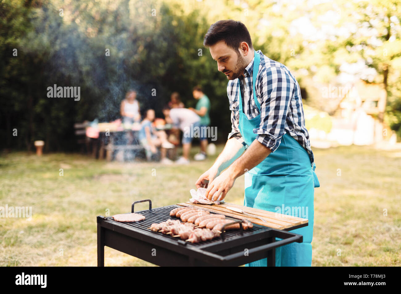 Bel maschio prepara barbecue in una foresta Foto Stock