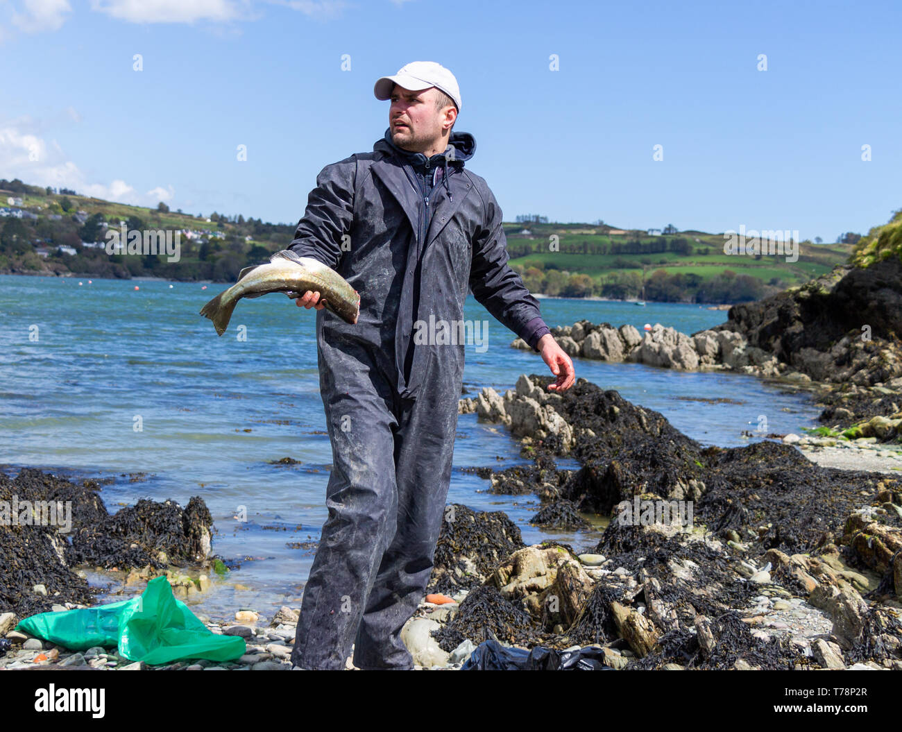 Mare maschio pescatore pulizia cattura la sua linea di pesce pescato in mare Foto Stock