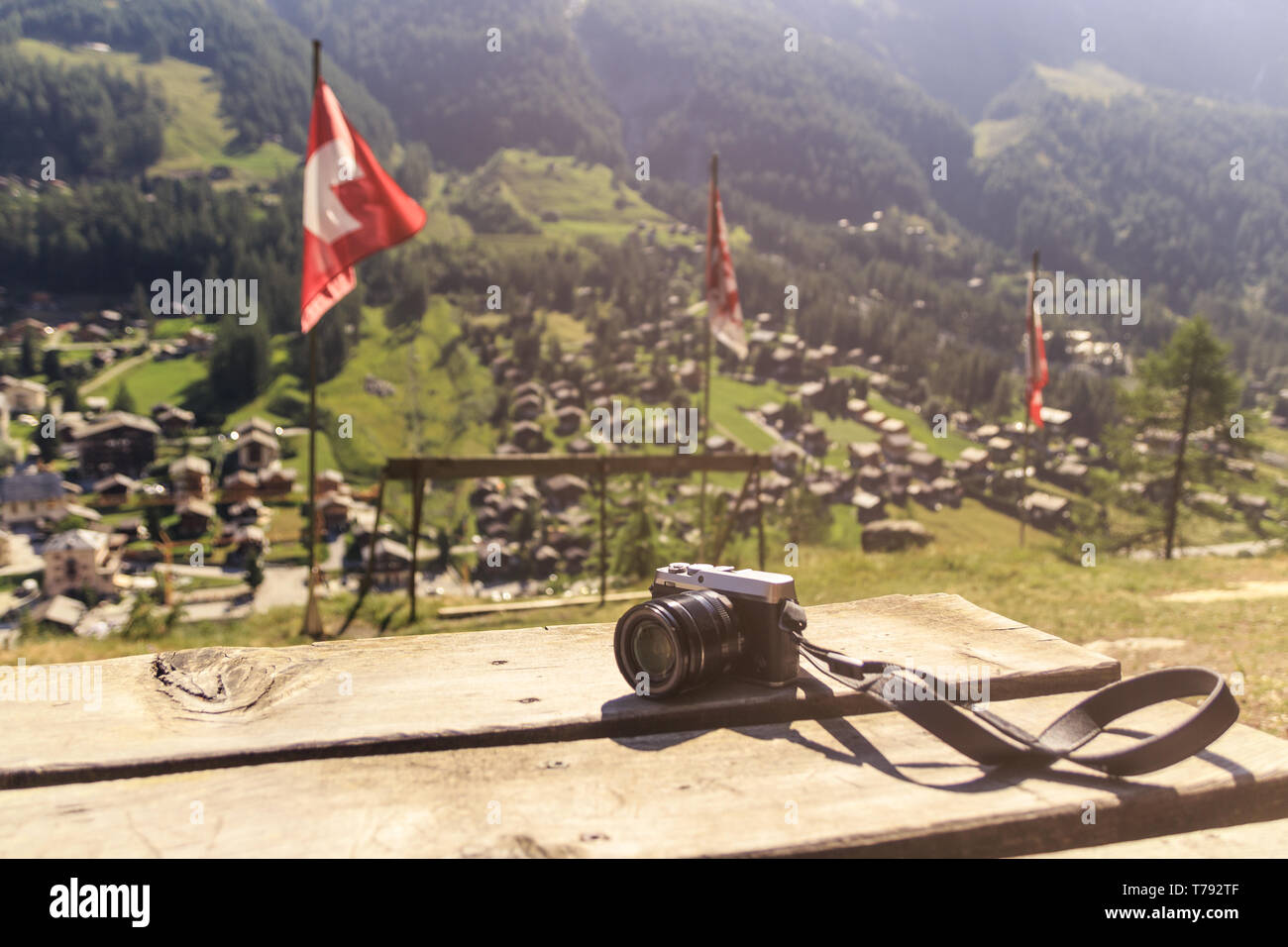 Un vintage cercando foto fotocamera su un tavolo di legno su un punto di vista sul villaggio alpino nelle Alpi Svizzere - estate concetto di viaggio Foto Stock