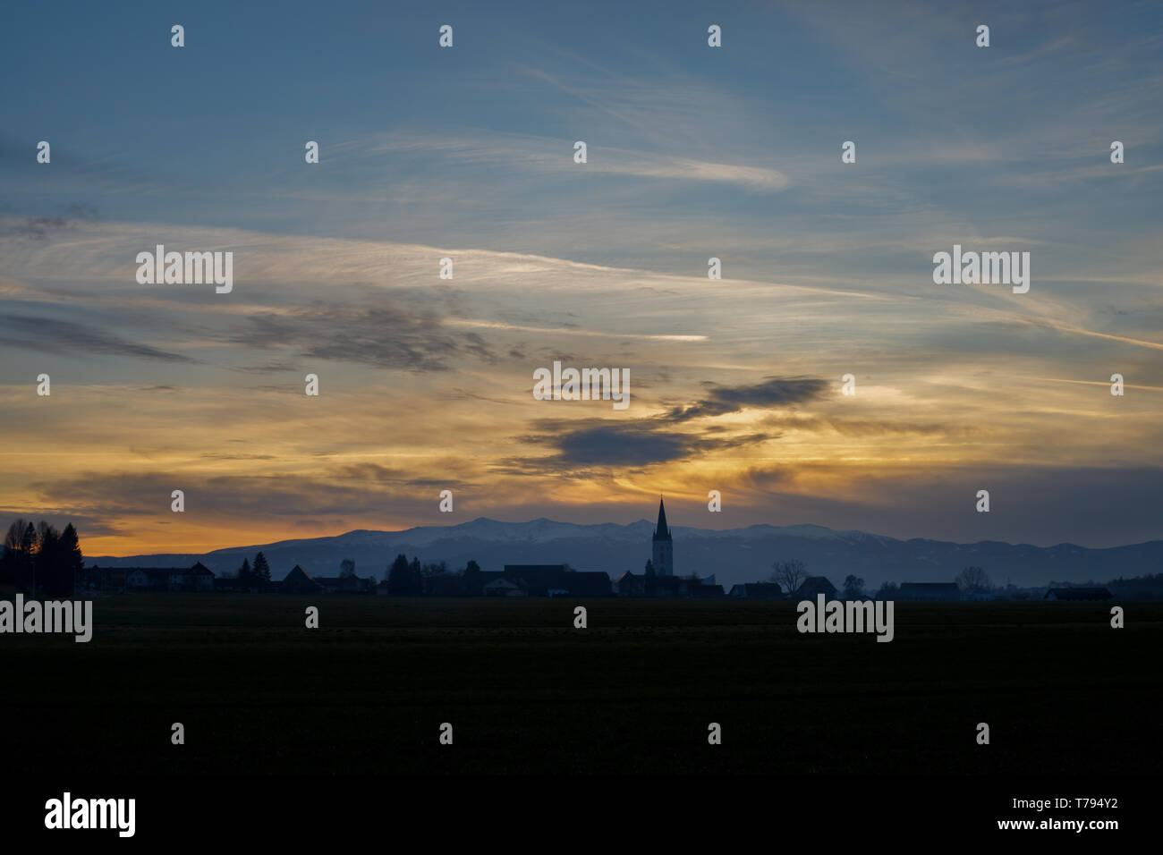 Tramonto colorato con diversi tipi di nuvole e una collina e valle silhouette con un campanile di una chiesa nelle alpi austriache in Stiria Foto Stock