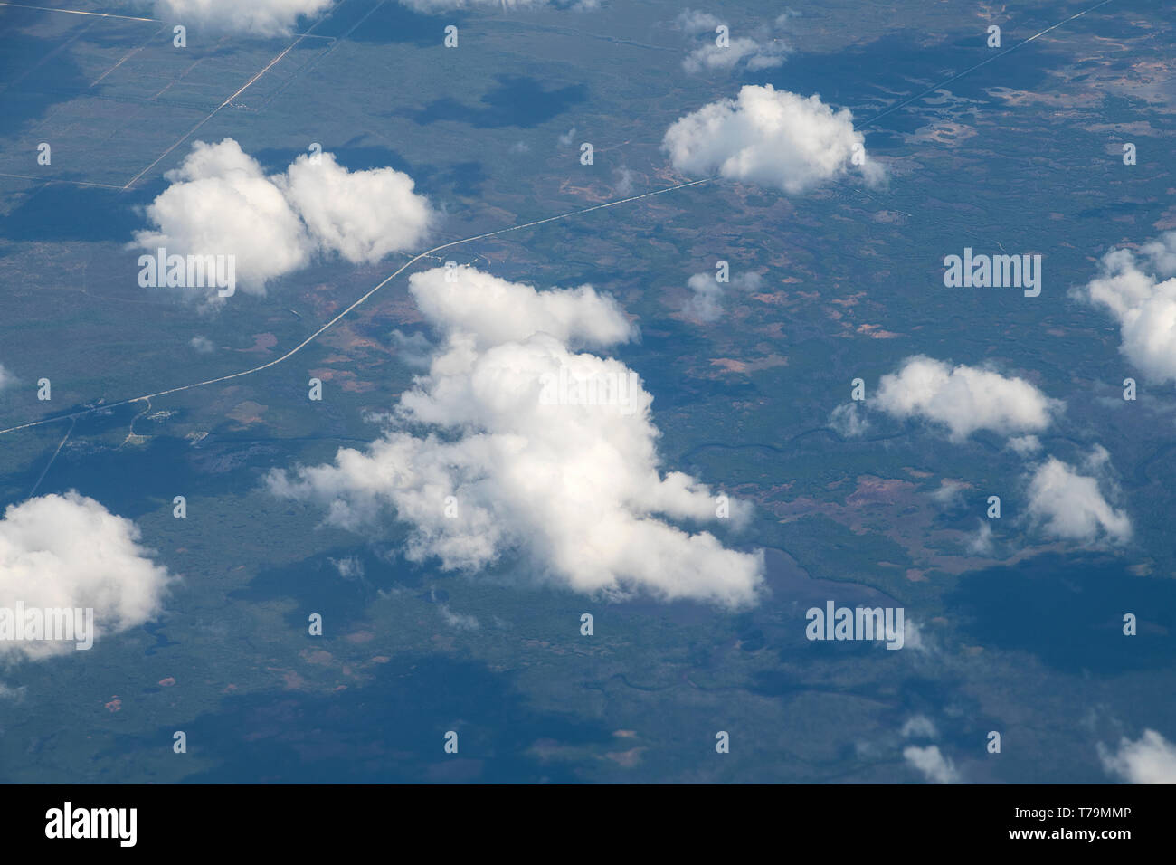 Vista aerea della terra con soffici nuvole con ombre dalla finestra di aeroplano Foto Stock