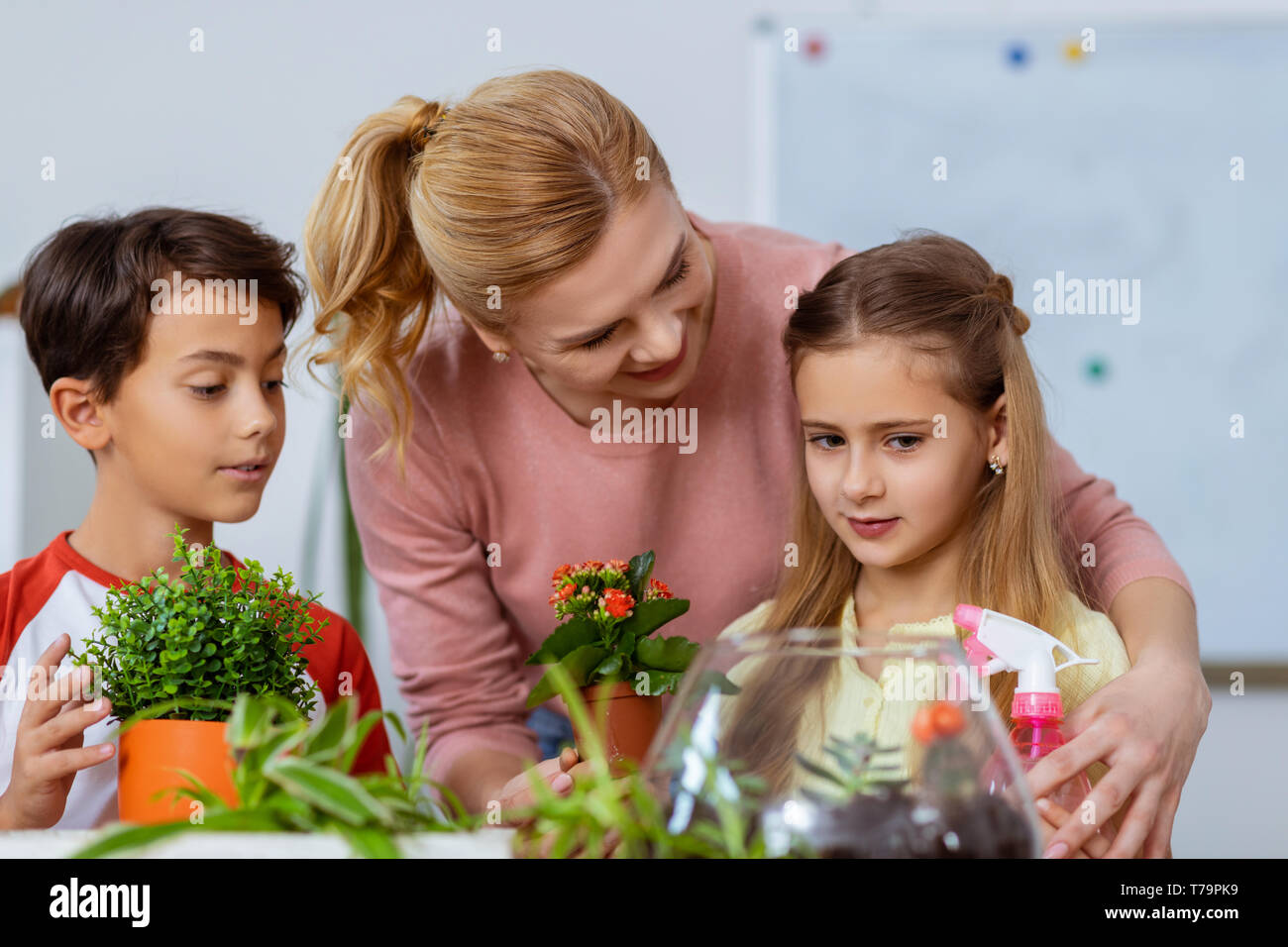 Abbracciando la ragazza carina. Disponibile bionda insegnante abbracciando la ragazza carina mentre piantare fiori con un ragazzo e una ragazza Foto Stock