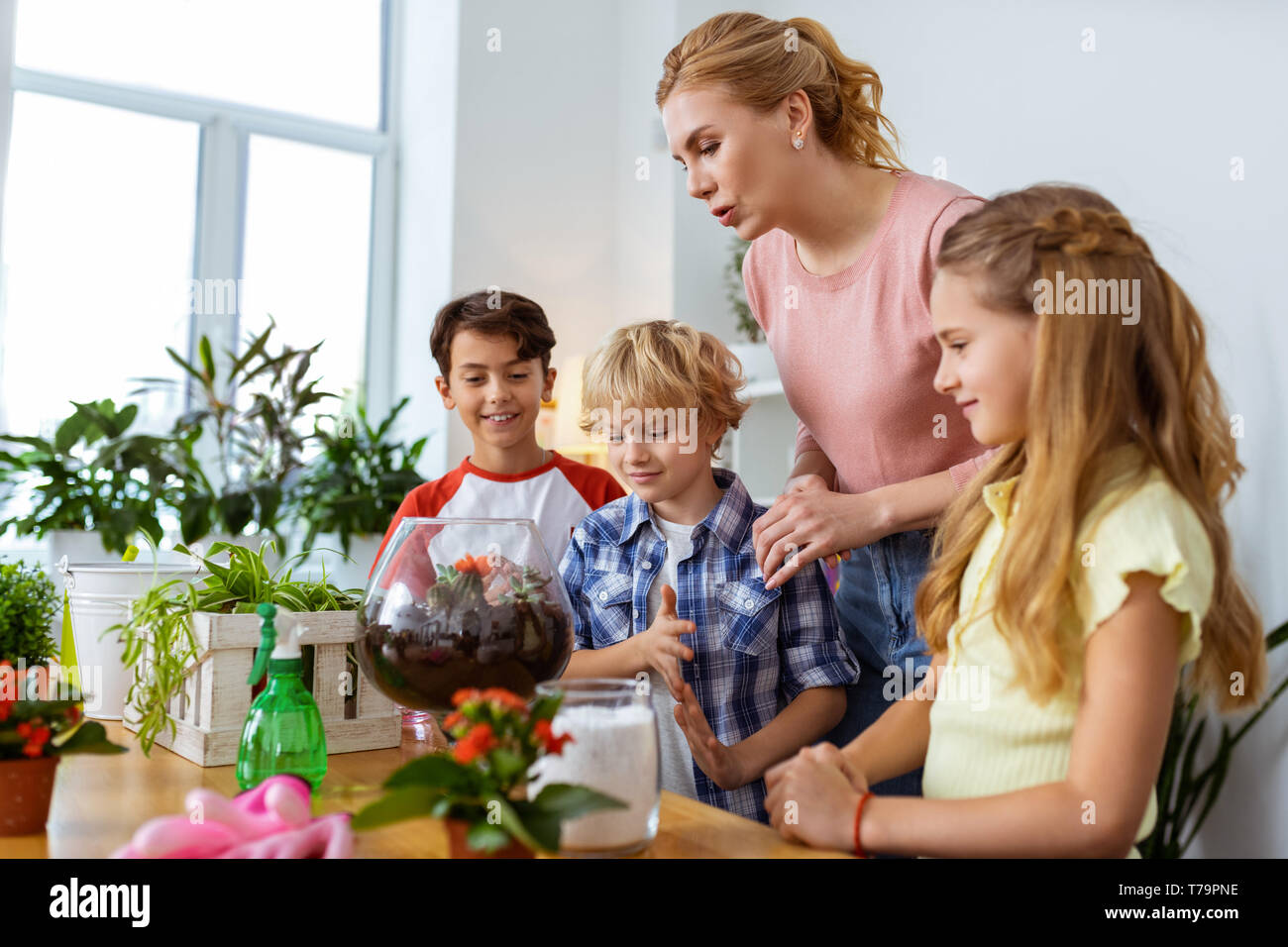 Insegnante e di ecologia. La bionda insegnante raccontando i suoi studenti circa i fiori e le piante a lezione di ecologia a scuola Foto Stock