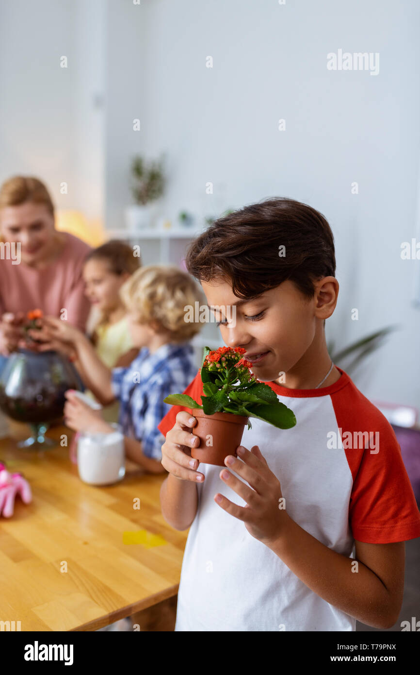 Odore di fiori. Carino bello ragazzo profumati fiori alla botanica lezione a scuola in piedi vicino a studenti e insegnanti Foto Stock